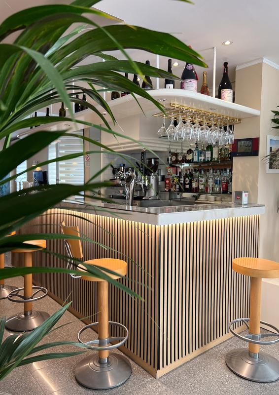 Modern bar with wooden stools and hanging glasses.